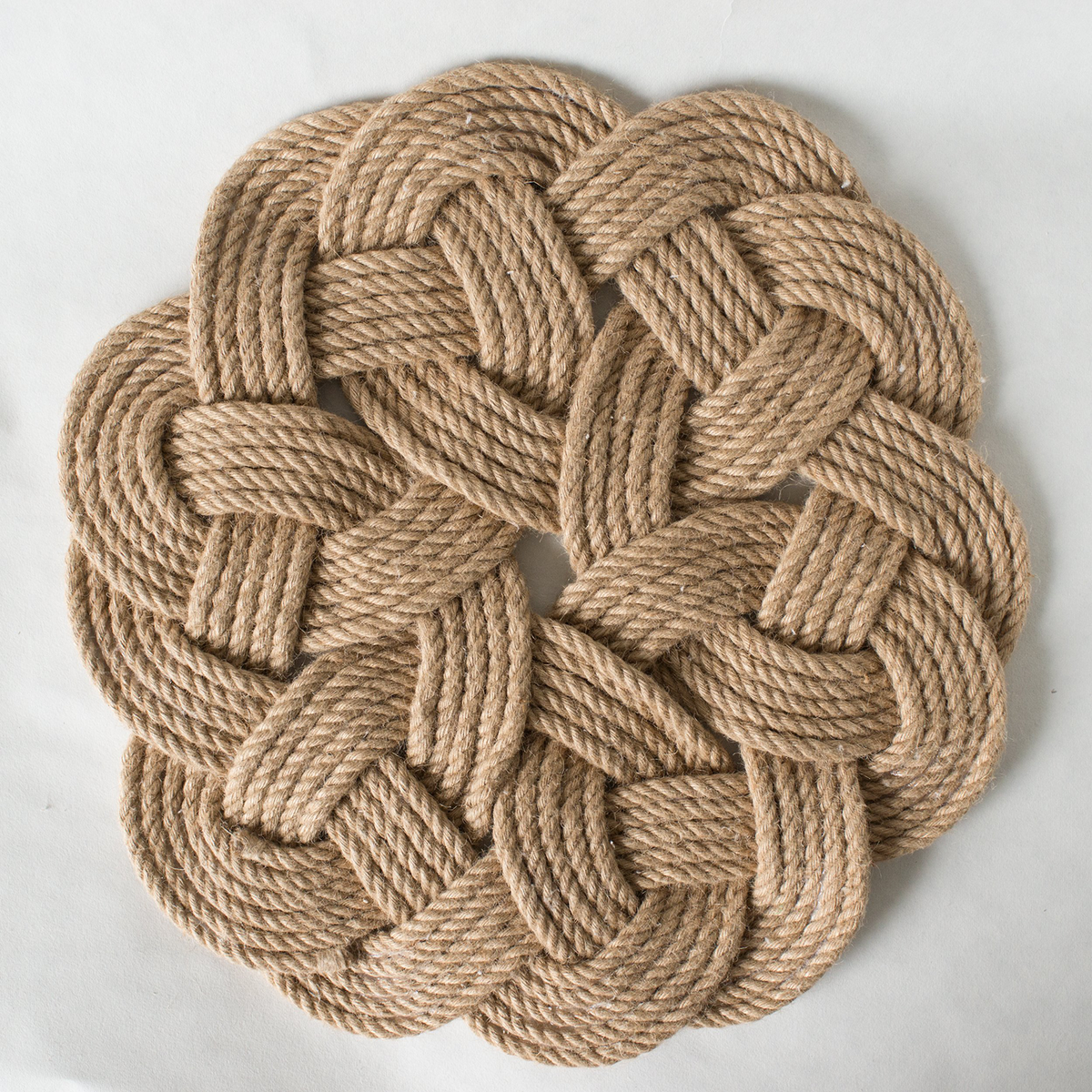 Natural rope mat with intricate braided knot design on white background