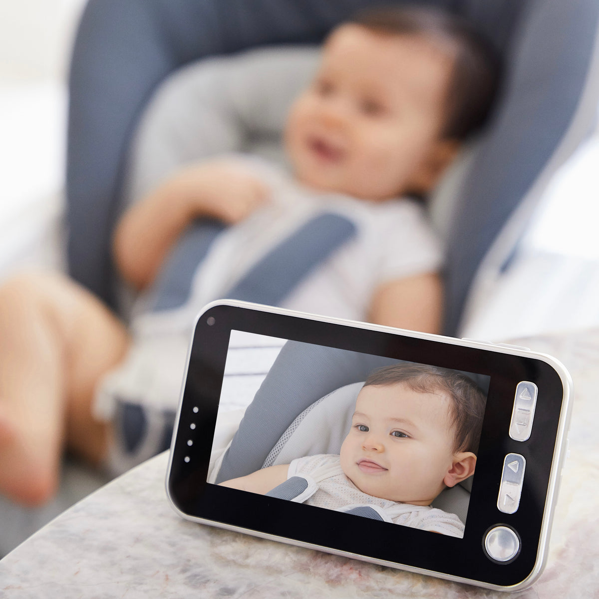 Baby in a travel car seat viewed on a portable monitor for travel safety products