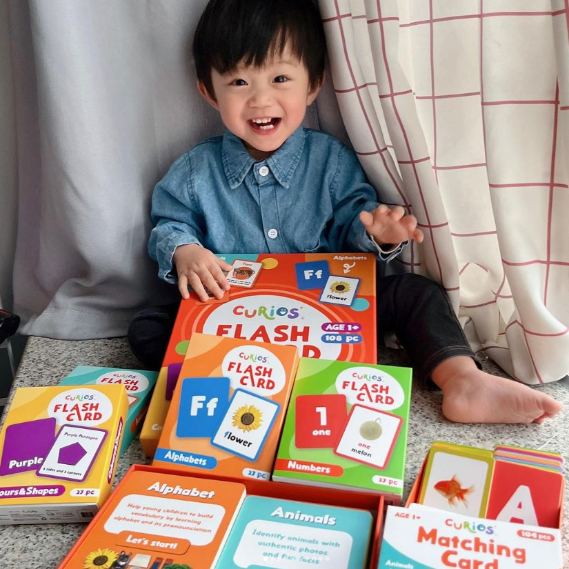 Smiling toddler with educational Curios flash cards for alphabet, numbers, and learning at home