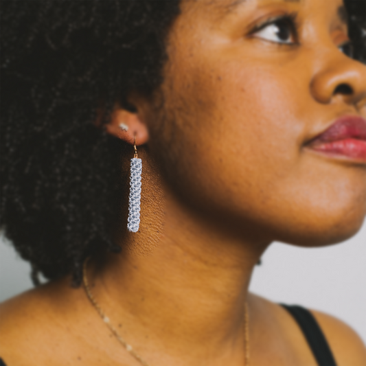 Woman wearing long silver crystal dangle earring, close-up side profile view