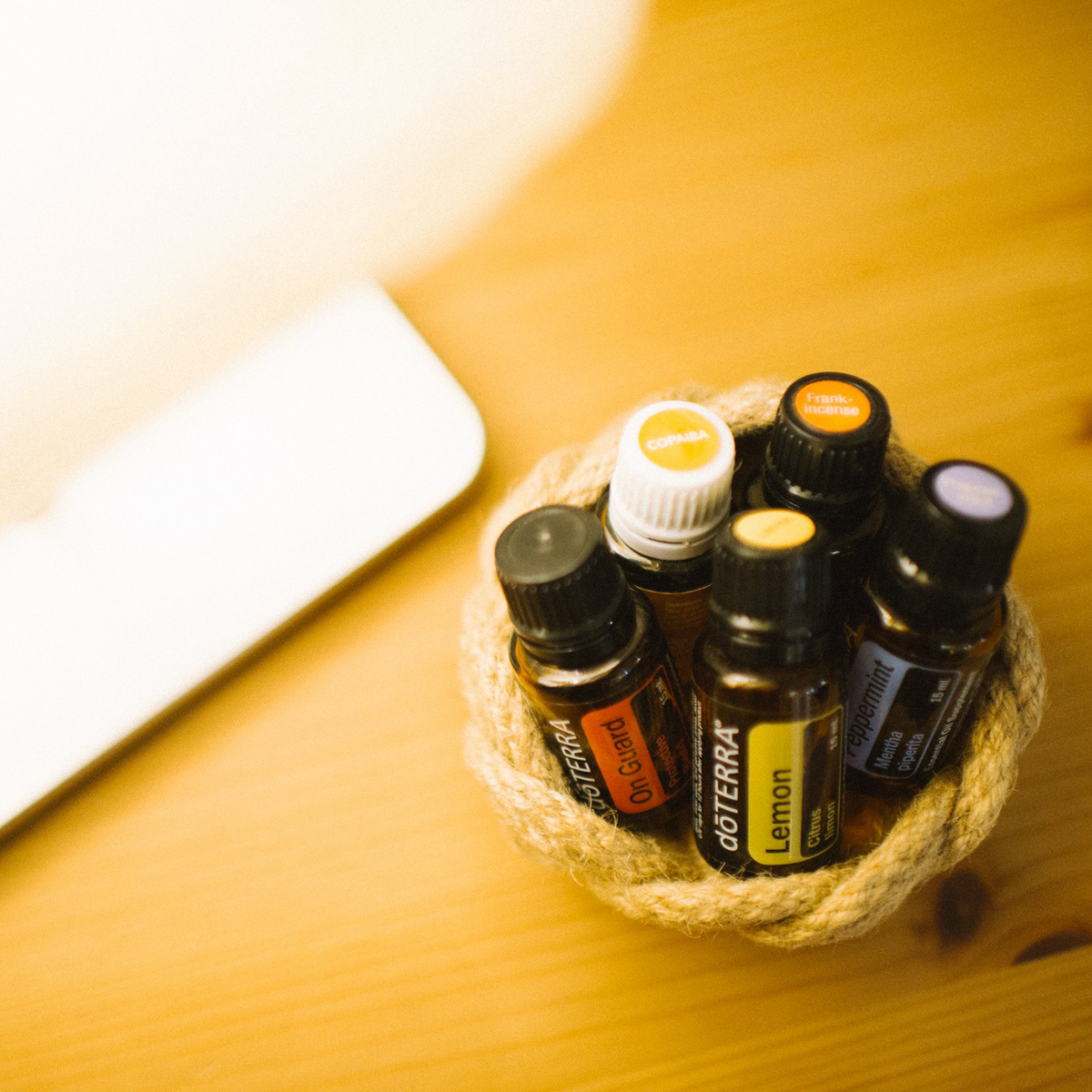 doTERRA essential oil bottles in rope basket on wooden table, citrus and herbal scents visible