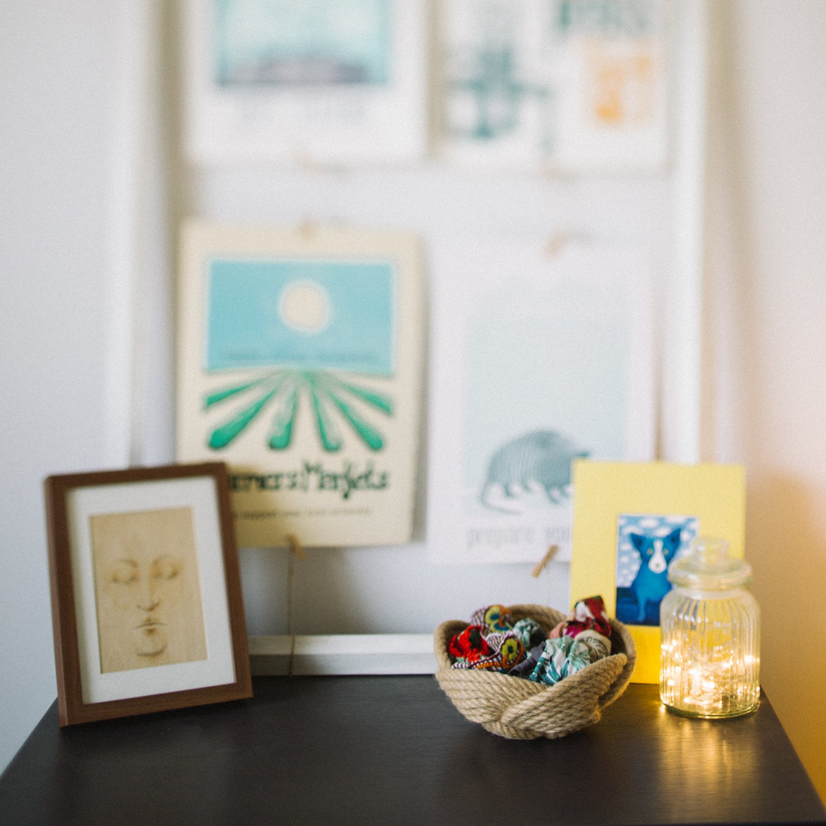 Framed art, colorful rope basket, and a jar with fairy lights on a modern shelf.