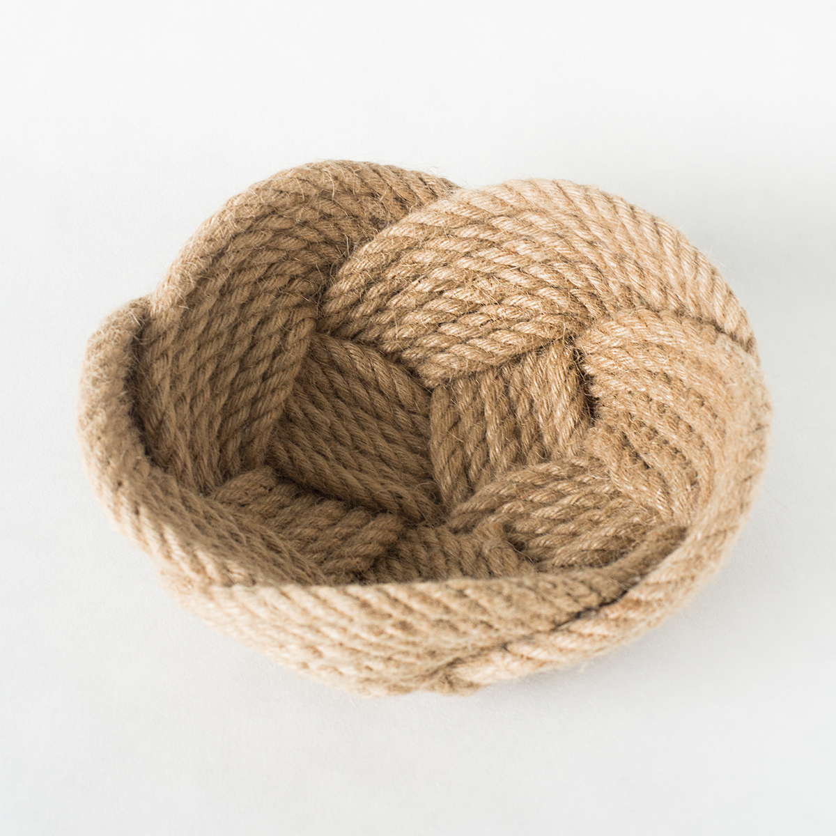 Woven rope bowl in natural beige, handmade basket on white background.