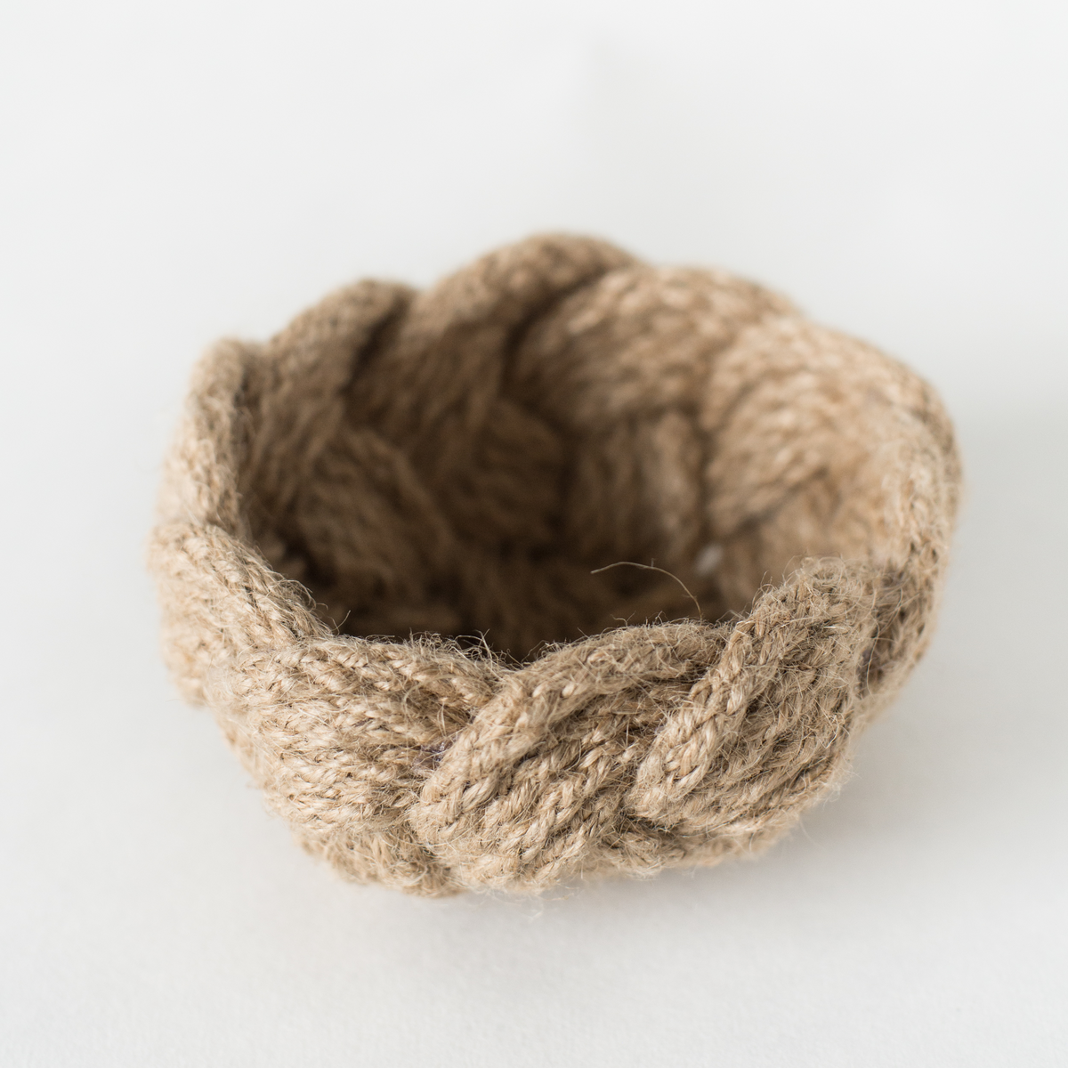 Small braided jute rope bowl on white background, rustic eco-friendly decor.