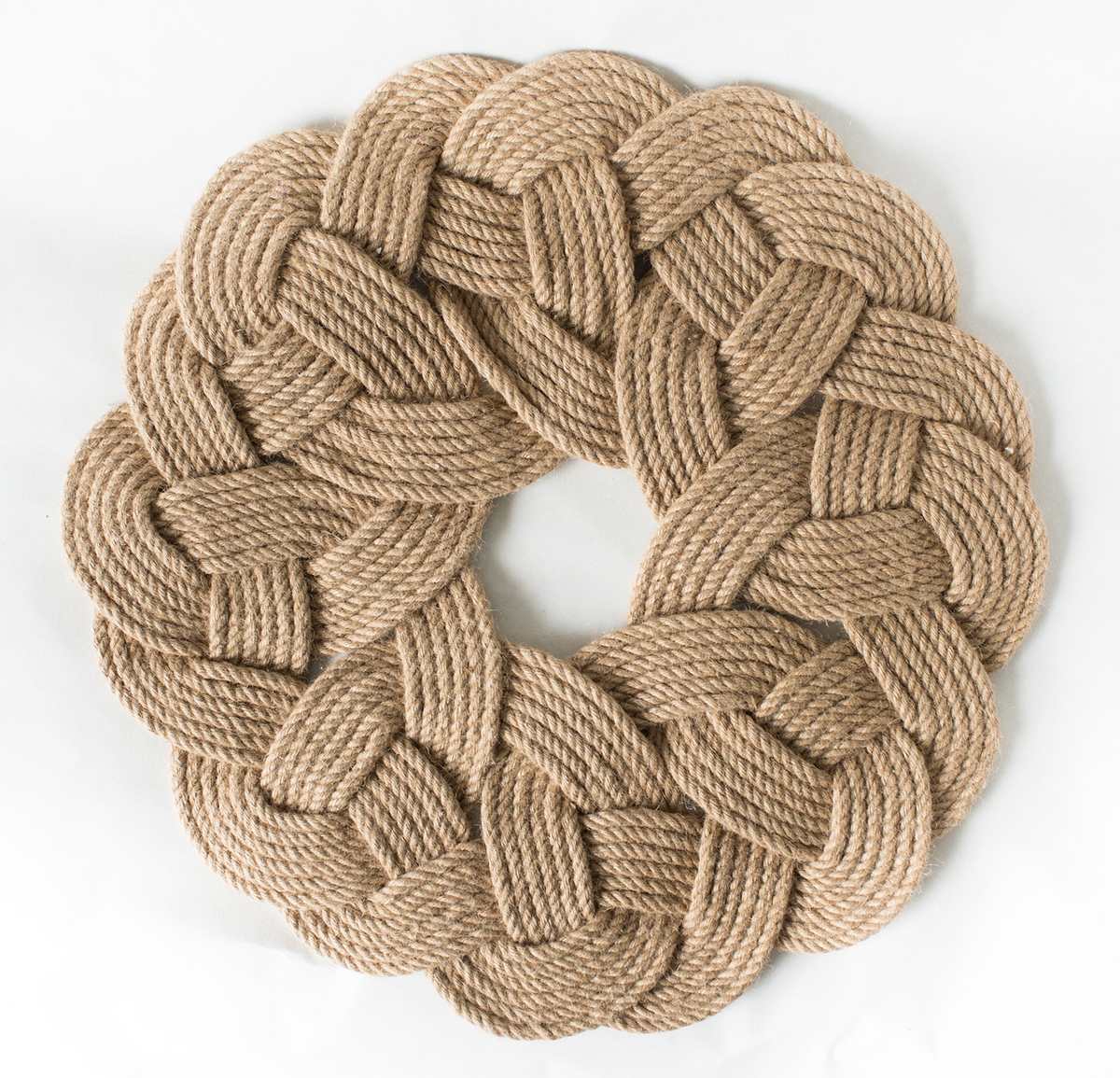 Round braided jute rope mat with a woven knot pattern on a white background