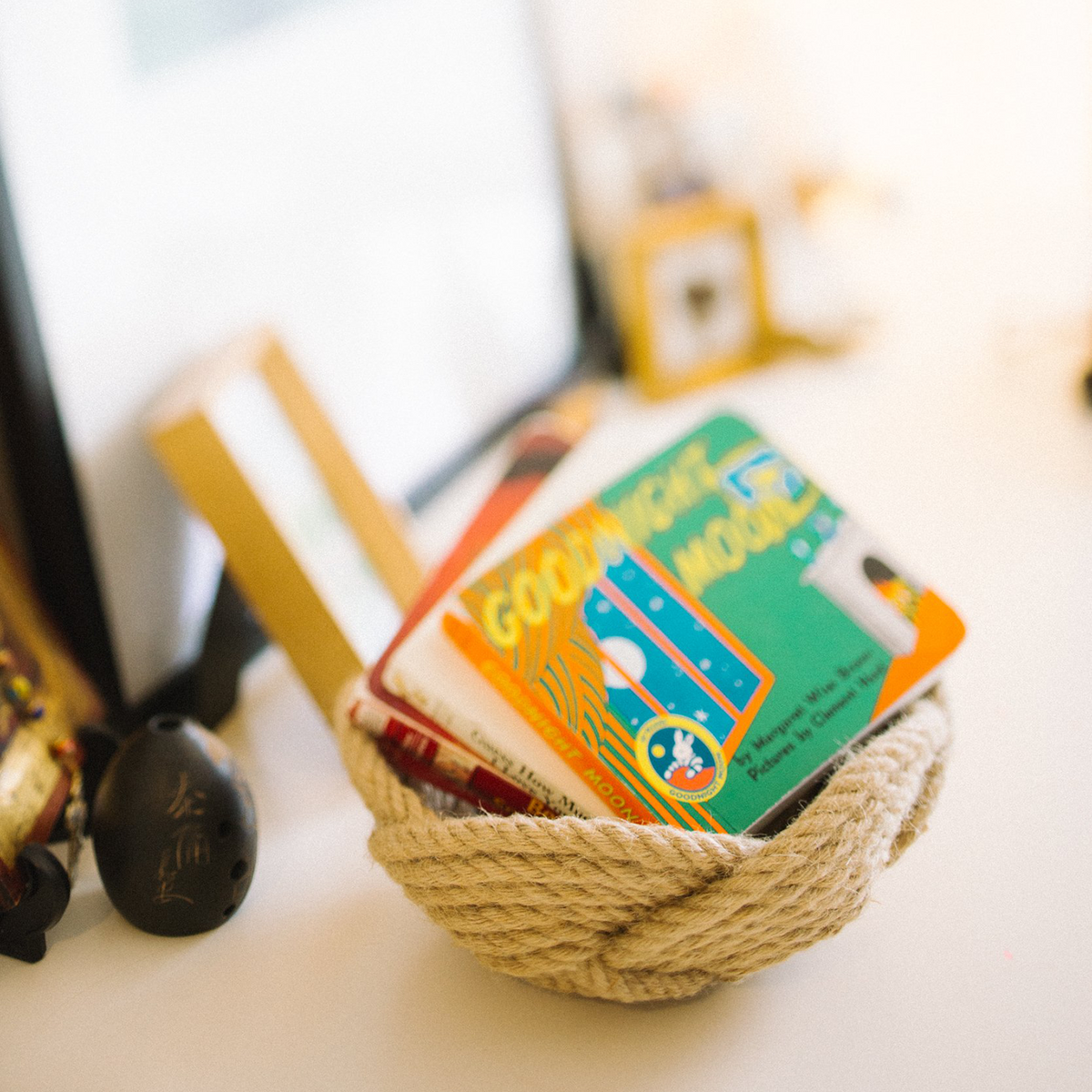 Children’s books, including 'Goodnight Moon', in a rope basket on a white table