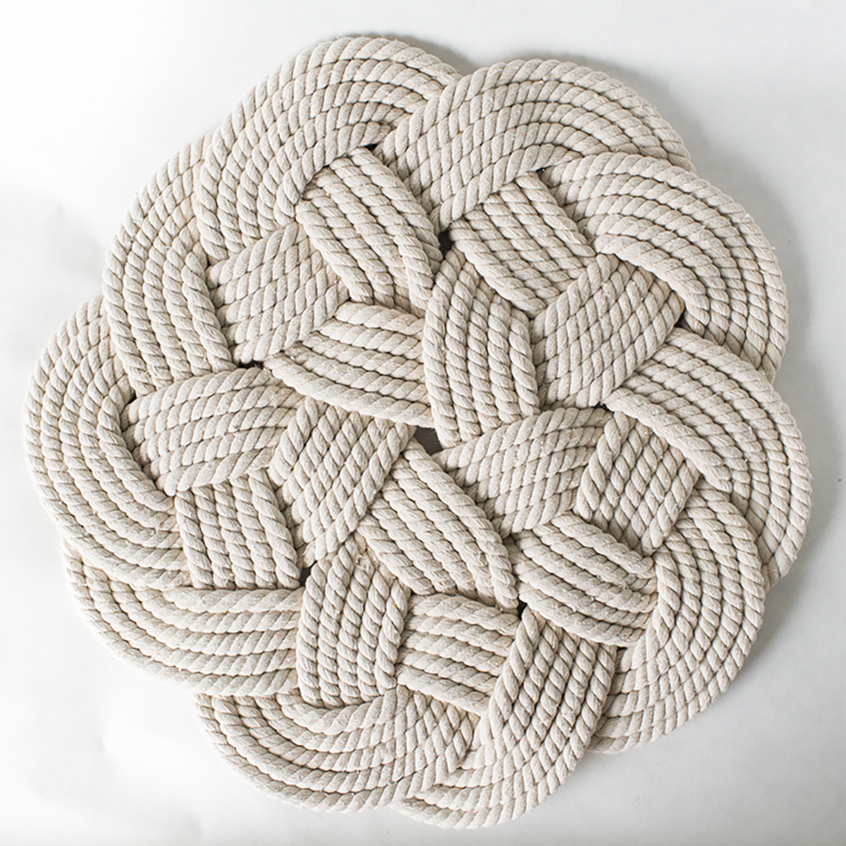 Round braided cotton rope rug with intricate knot pattern on a white background