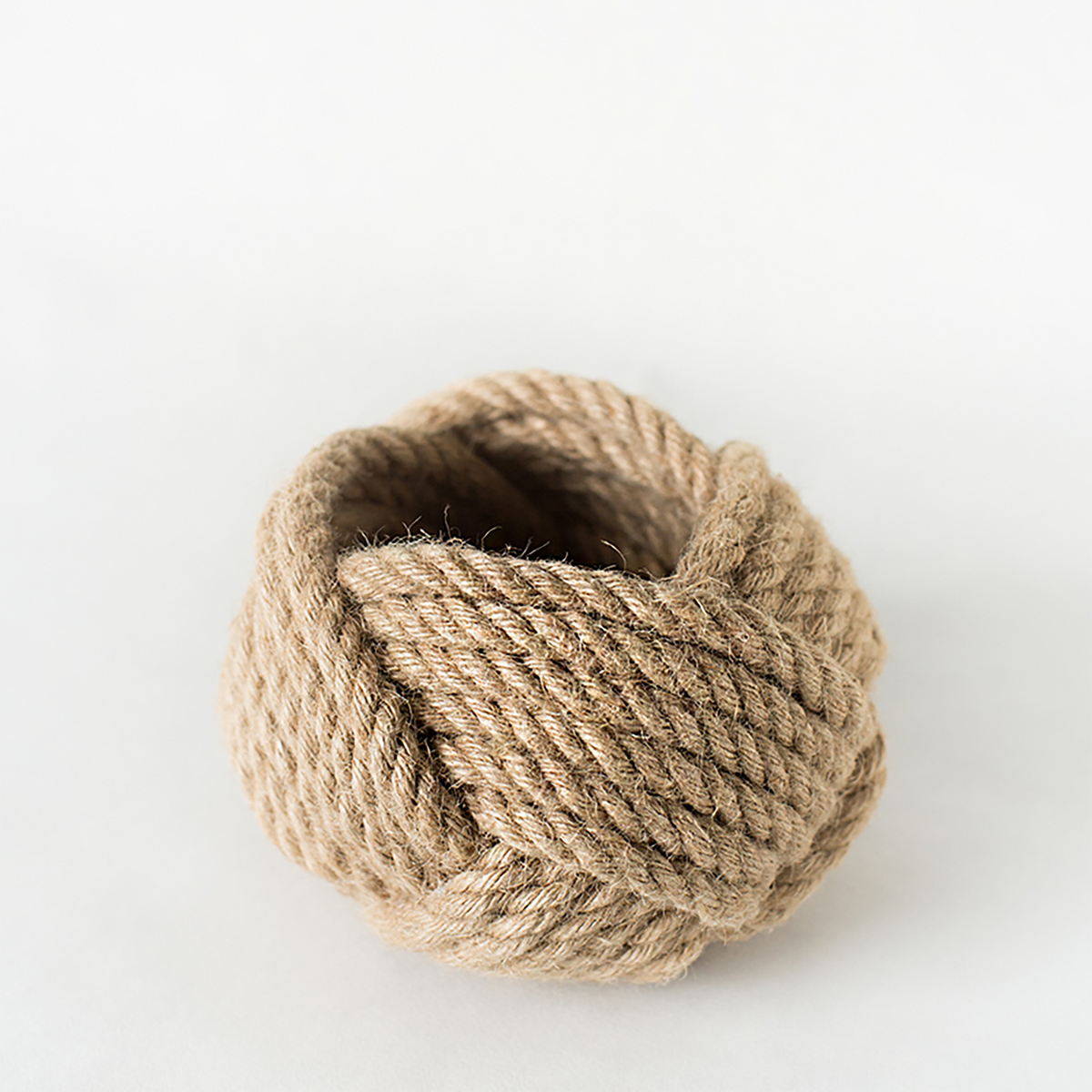 Close-up of a monkey knot rope ball on a white background, portable travel accessory.